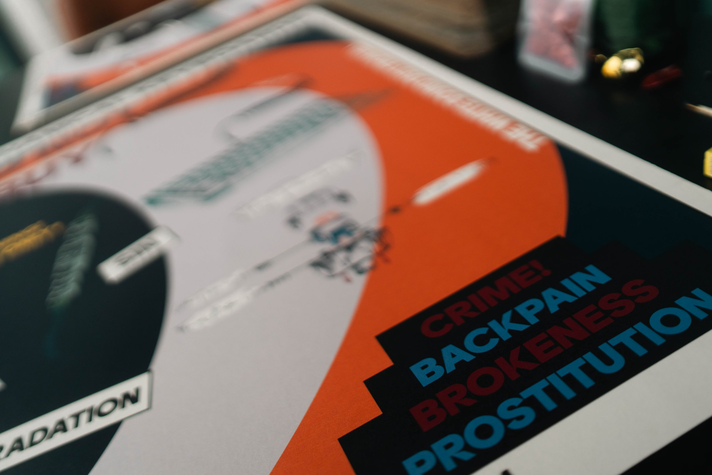 Close-up of the lithograph ; the CRIME BACKPAIN BROKENESS PROSTITUTION warning block stacked against an orange curve